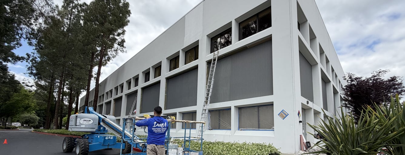 Diaz painter preparing an office building exterior with a boom lift