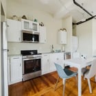 Apt 201 kitchen with white cabinets, gas range and dining table