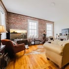Living room in Apartment 301 with exposed brick walls, two tall windows and original hardwood floors