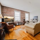 Wide view of the living room in Apartment 301 with brick walls, hardwood floors and exposed ductwork