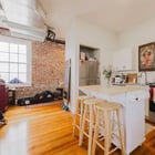 Kitchen in Apartment 301 with a breakfast bar and stools, stainless range and microwave, and brick wall beyond
