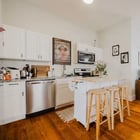 Kitchen in Apartment 301 with white shaker cabinets, stainless dishwasher and range, and a breakfast bar