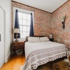 Bedroom in Apartment 301 with exposed brick walls, two windows and hardwood floors