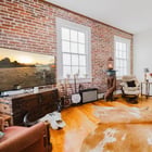 Living room in Apartment 301 with a brick wall, two windows and a decorative fireplace