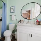 Bathroom in Apartment 301 with a walk-in shower, vanity with stone counter and round mirror