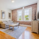 Apartment 303 living room with sectional sofa, exposed brick wall and view into the bedroom