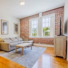 Apartment 303 living room with lamp, sectional sofa and exposed brick