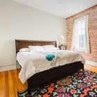 Apartment 303 bedroom with wood dresser and exposed brick wall