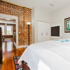 Apartment 303 bedroom with white bedding and exposed brick