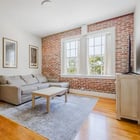 Apartment 303 living room with sectional sofa, exposed brick wall and tall windows