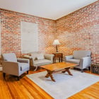 Apartment 303 sitting area with armchairs, coffee table and exposed brick