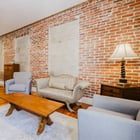 Apartment 303 bedroom with seating area and exposed brick walls