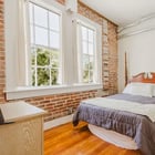 Apartment 303 bedroom with exposed brick wall and tall windows