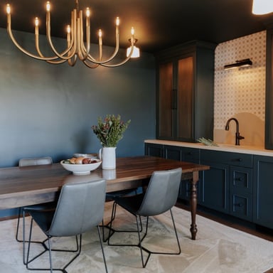 Dining room painted deep teal with brass chandelier