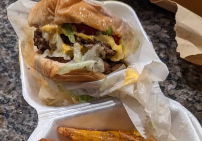 Chili cheese fries and a cheeseburger in takeout containers