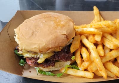 A cheeseburger and fries in a paper tray