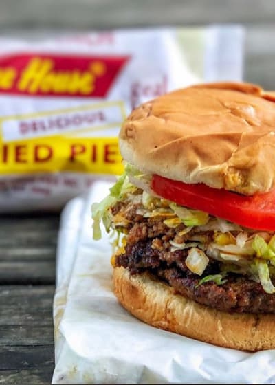 A cheeseburger with lettuce and tomato next to a fried pie