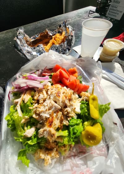A Greek salad topped with grilled chicken and pepperoncini
