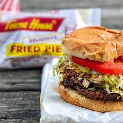 A cheeseburger with lettuce and tomato next to a fried pie