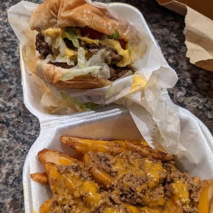 Chili cheese fries and a cheeseburger in takeout containers