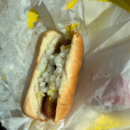 A hot dog with chili, mustard and diced onions