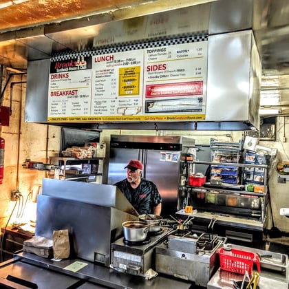 The kitchen behind the counter, under the menu board