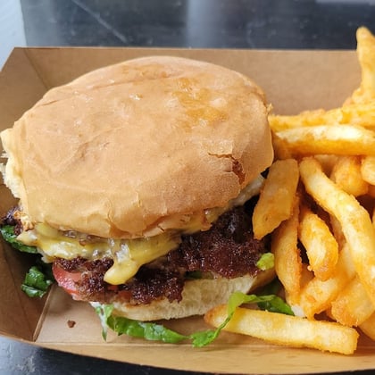 A cheeseburger and fries in a paper tray