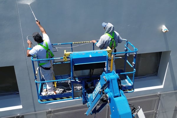 Two Diaz painters spraying an office wall from a boom lift