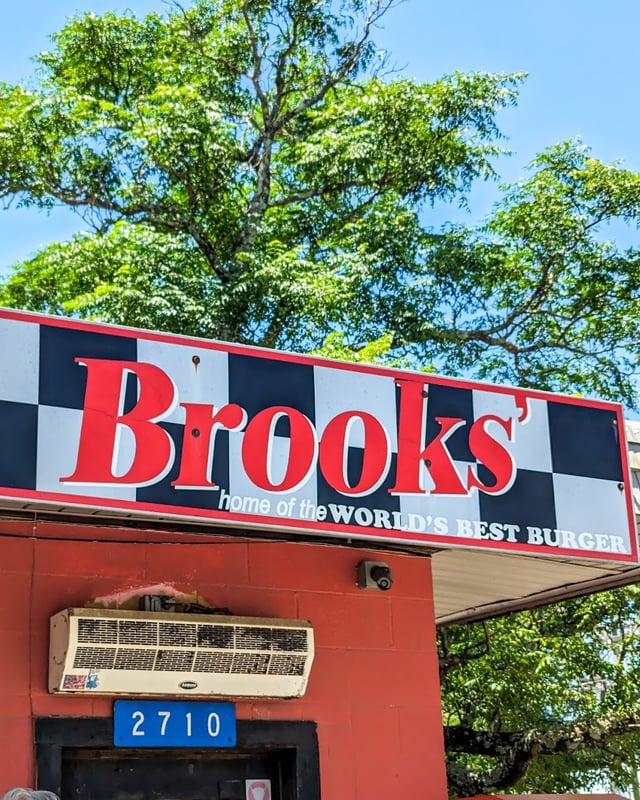 The checkered Brooks' sign over the red cinder-block stand, under a big shade tree