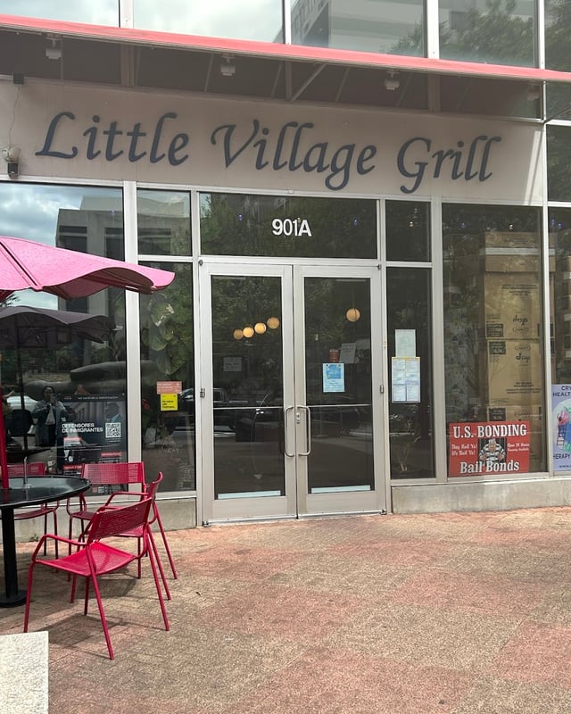 The Little Village Grill storefront on East 4th Street, with red patio chairs out front