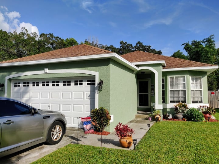 The same home after being painted sage green with white trim