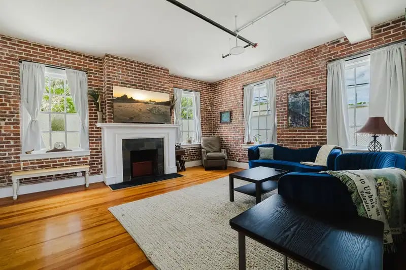 Apartment 201 living room with decorative fireplace and brick walls