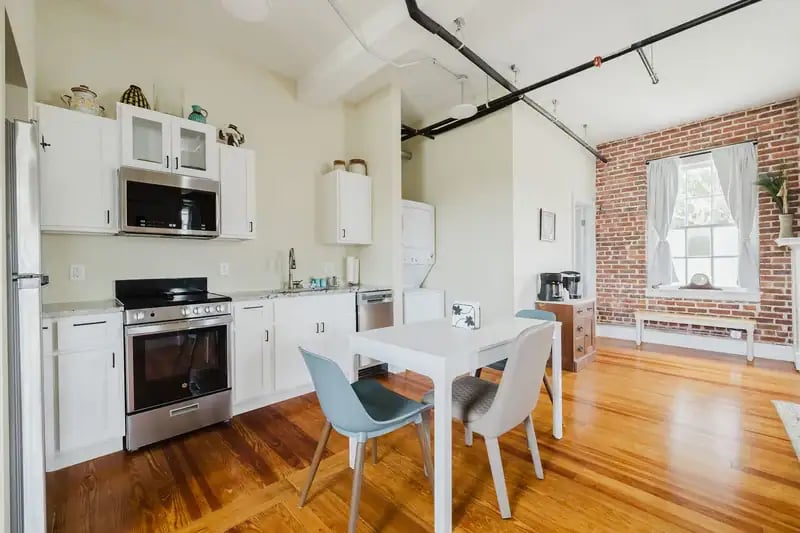 Apartment 201 kitchen with white cabinets, gas range and dining table
