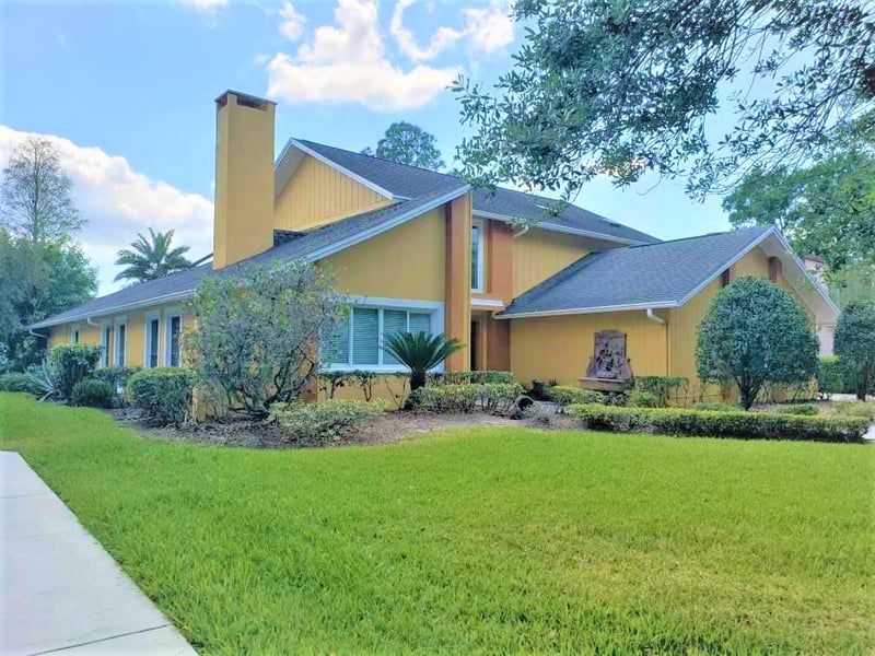 Two-story Florida home freshly painted in yellow with orange trim