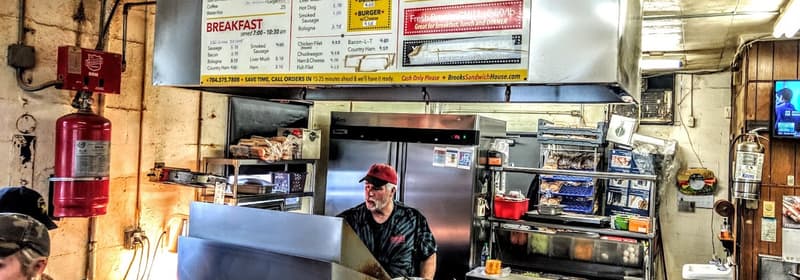 The kitchen behind the counter, under the menu board